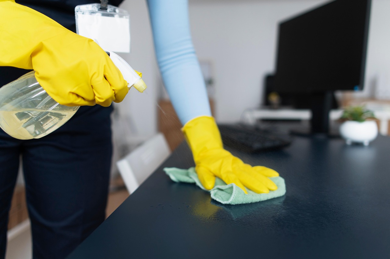 Reinigung eines Büroschreibtisches mit Tuch und Sprühflasche